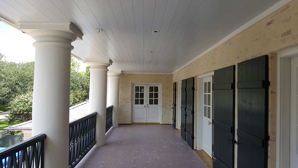 A porch with two doors and a railing.