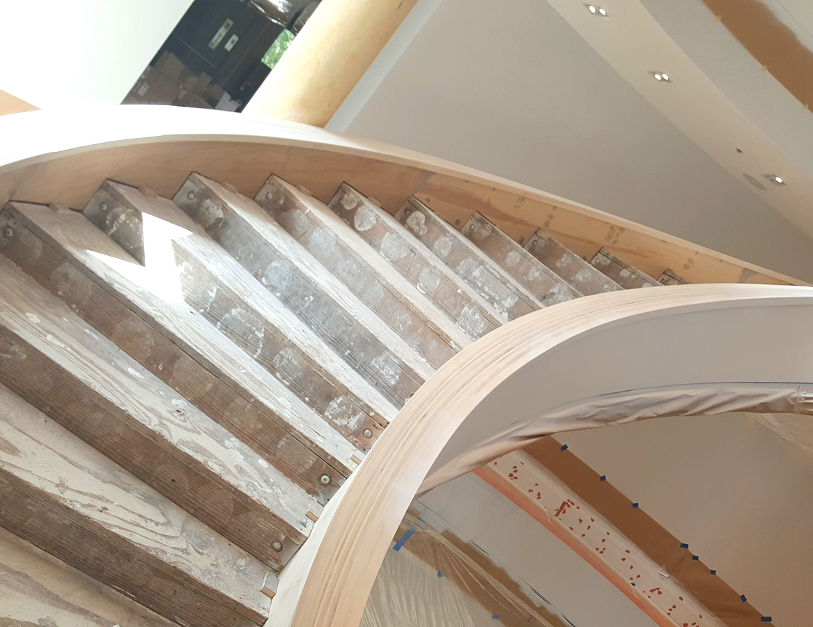 A spiral staircase with wooden steps and white treads.