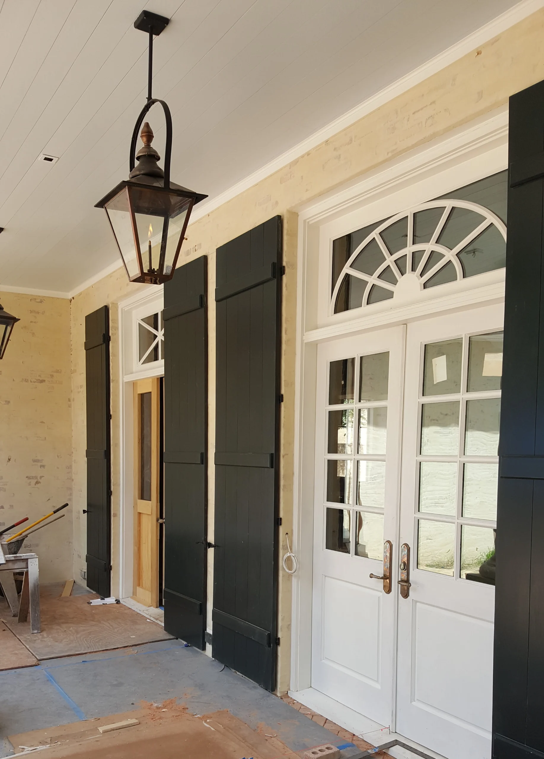 A porch with black shutters and a lantern.